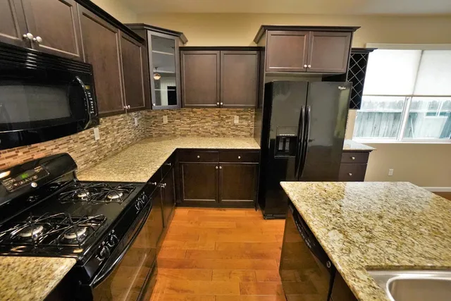 a view of an empty room with kitchen appliances and a ceiling fan