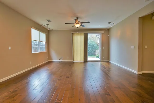 a view of an empty room with window and wooden floor