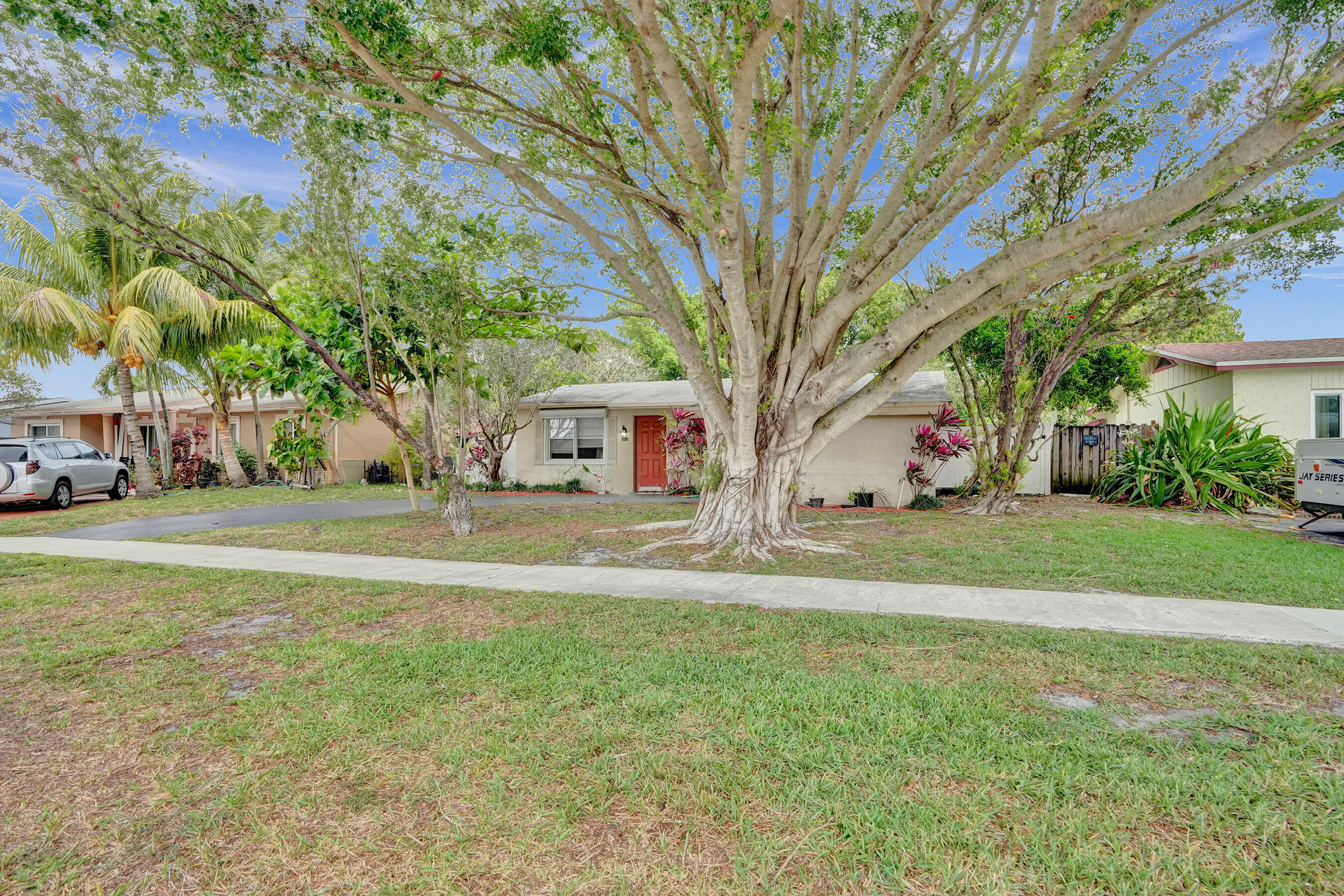 7697 Forest Boulevard North Lauderdale, FL 33068 - Photo 5 of 30 a view of a white house with a big yard and large trees