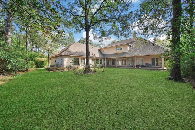 a view of a house next to a big yard and large trees