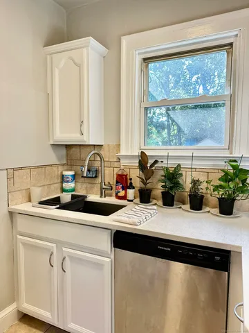 a kitchen with a sink a stove and white cabinets