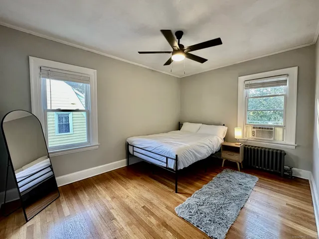 a bedroom with a bed wooden floor and windows