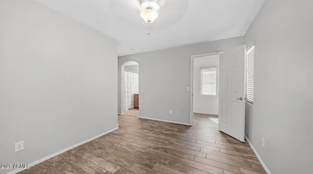 an empty room with wooden floor and windows
