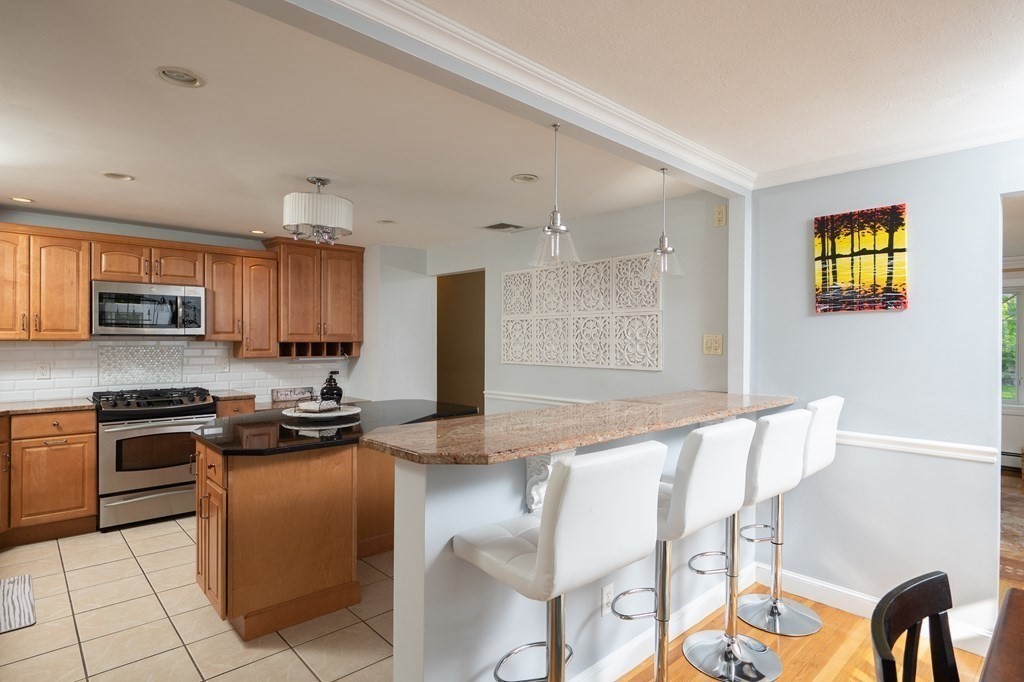 21 Harvest Lane Hingham, MA 02043 - Photo 5 of 35 a kitchen with stainless steel appliances granite countertop a stove top oven a sink a dining table and chairs with wooden floor