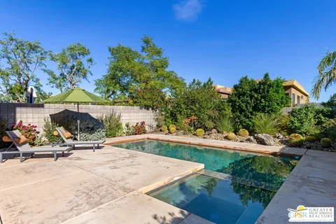 a view of a swimming pool with lawn chairs under an umbrella