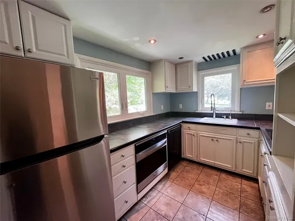 a kitchen with granite countertop a refrigerator a sink and wooden cabinets