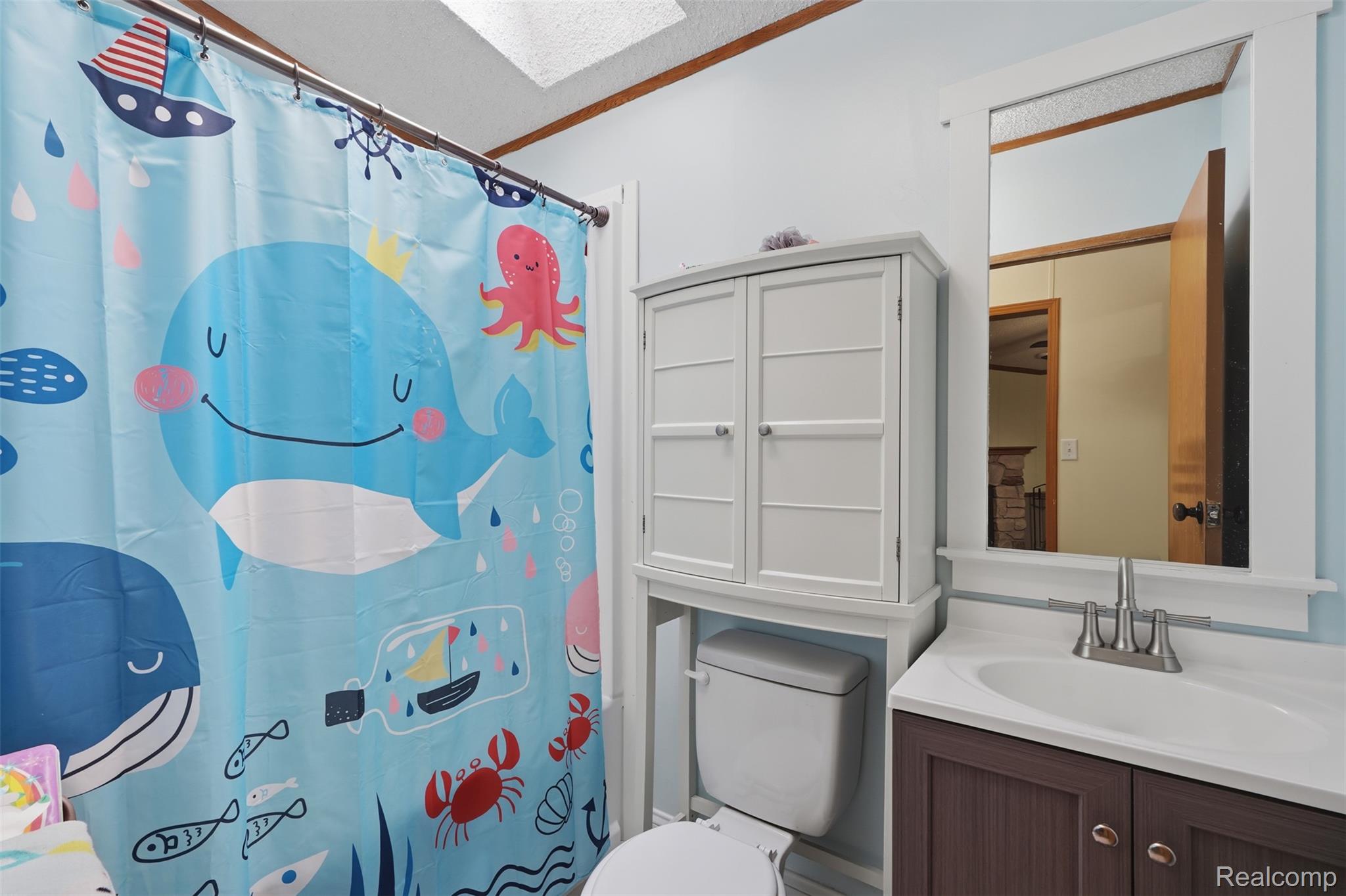 4634 Butternut Street Clarkston, MI 48348 - Photo 20 of 28 Bathroom featuring a white ceiling light fixture, white framed mirror, and built-in white over-toilet cabinetry