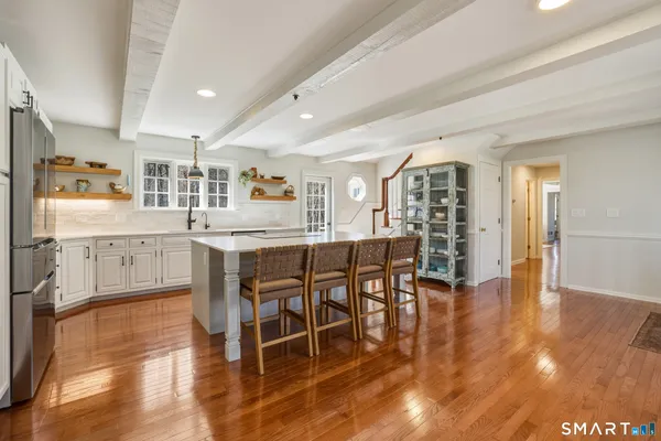 a living room with stainless steel appliances kitchen island granite countertop furniture and wooden floor