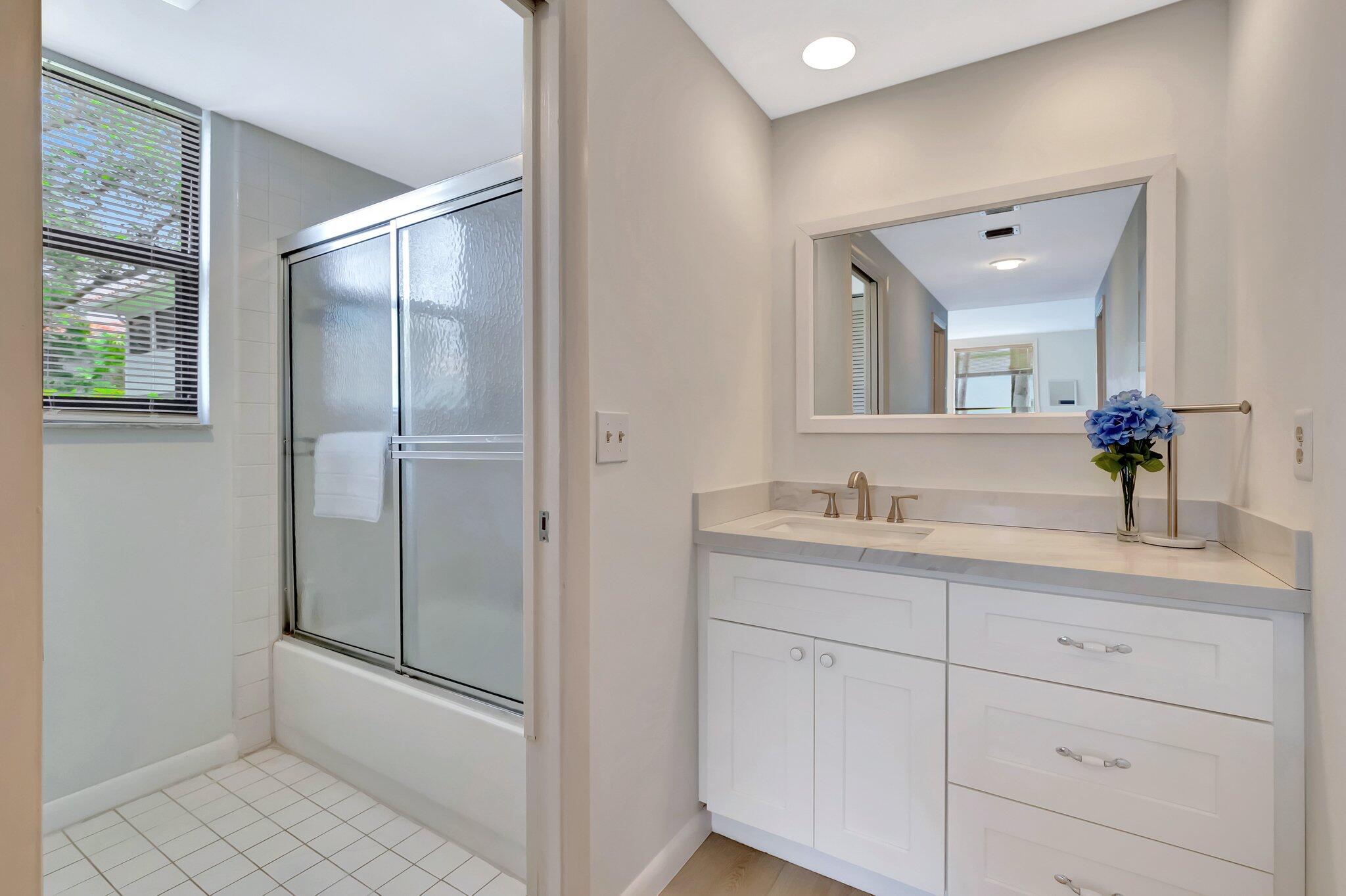 19819 Boca W Drive, Unit 4033 Boca Raton, FL 33434 - Photo 25 of 58 a bathroom with a double vanity sink and mirror