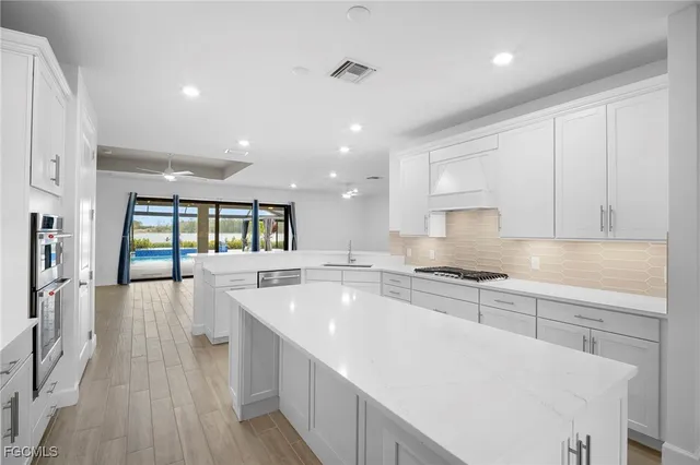 a large kitchen with stainless steel appliances granite countertop a lot of counter space and wooden floors
