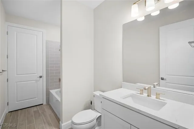 a bathroom with a granite countertop sink a toilet a mirror and shower