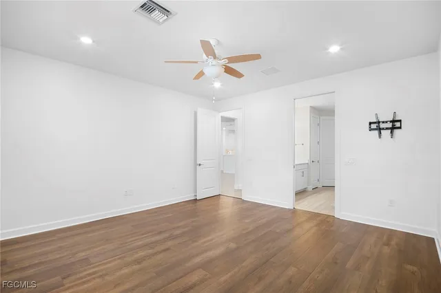 an empty room with wooden floor ceiling fan and windows