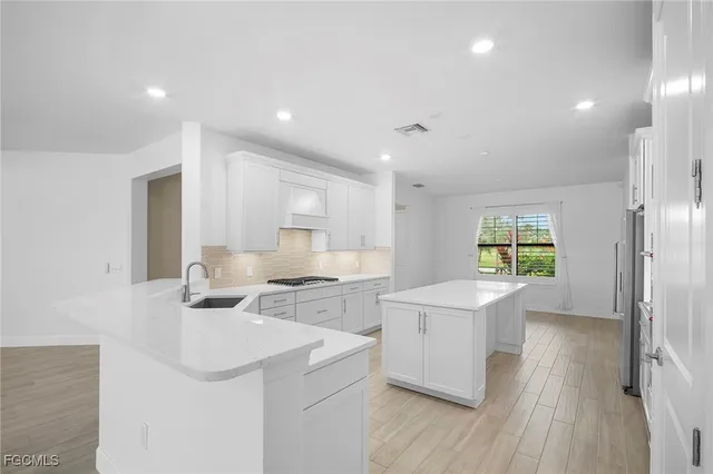 a kitchen with a sink a stove a refrigerator and white cabinets