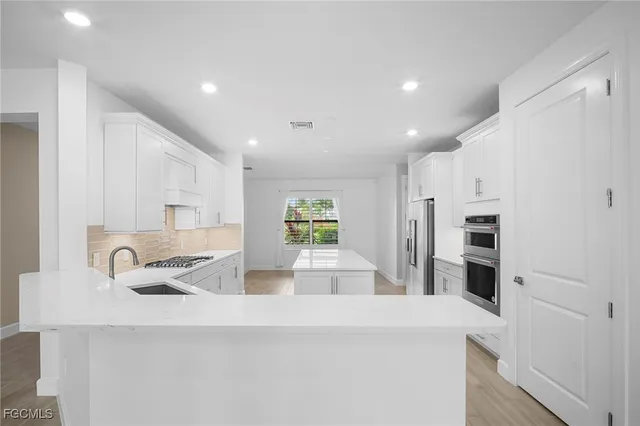 a kitchen with stainless steel appliances granite countertop a sink and a refrigerator