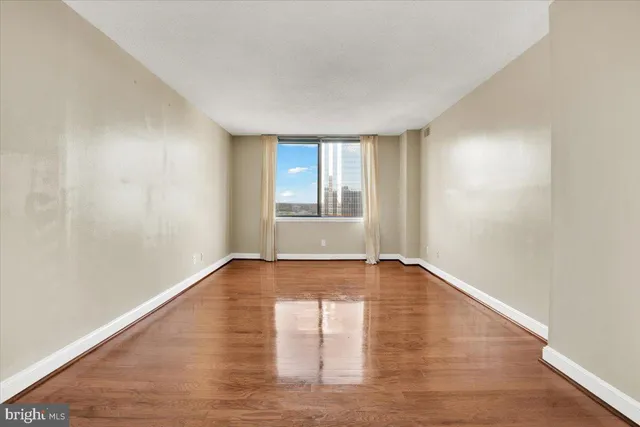 an empty room with wooden floor and windows