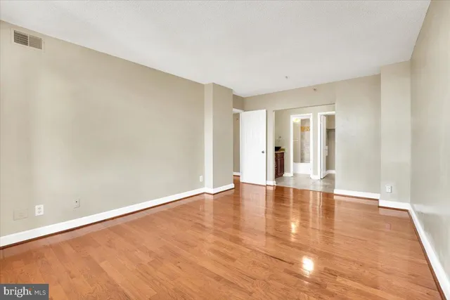 a view of an empty room with window and wooden floor