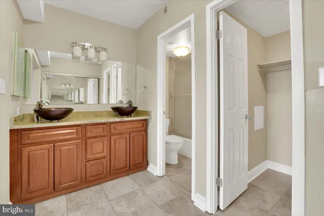 a spacious bathroom with a granite countertop sink a mirror and a toilet
