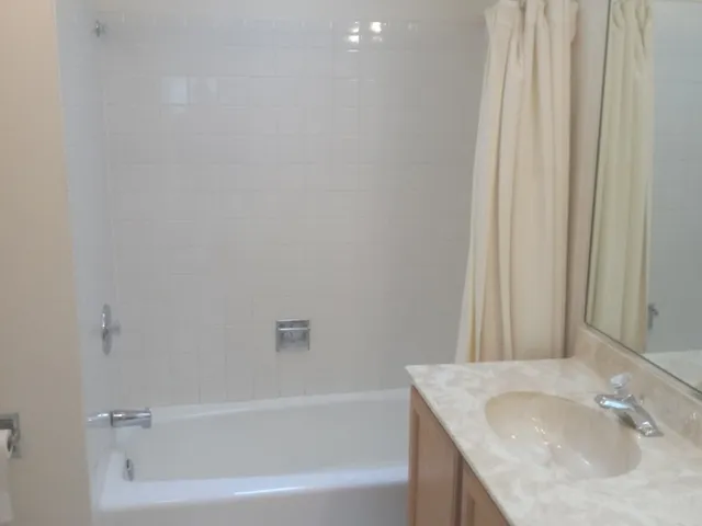 a bathroom with a granite countertop sink and a bathtub