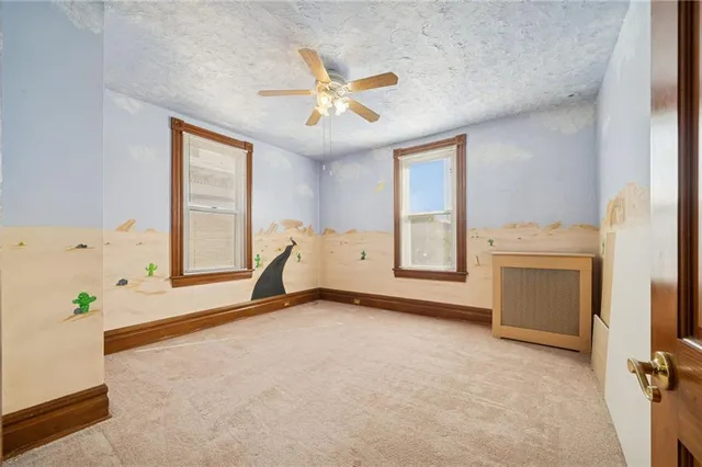 an empty room with windows and ceiling fan