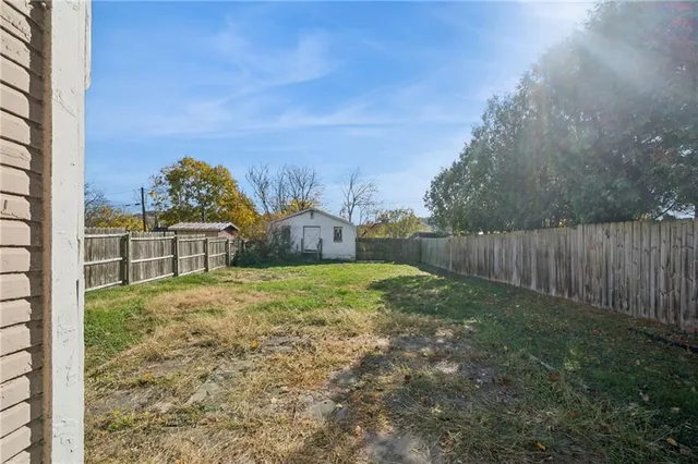 a view of a yard in front of a house with a large tree