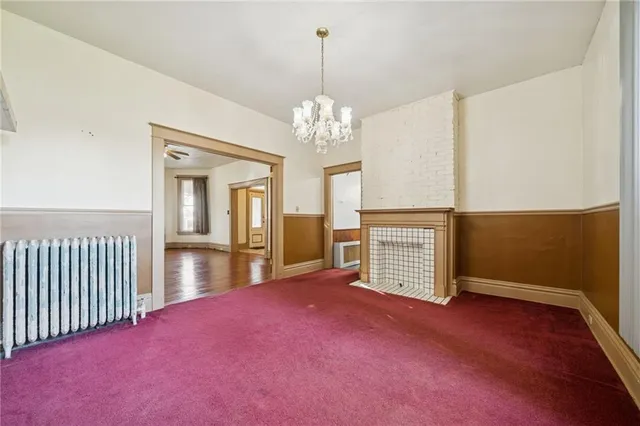 a view of an empty room with chandelier and a window