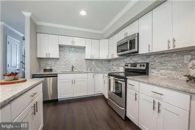 a kitchen with stainless steel appliances granite countertop a sink a stove a microwave and wooden cabinets