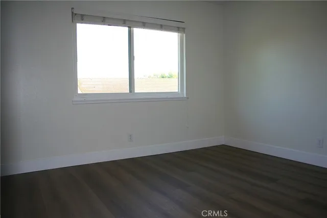 an empty room with wooden floor cabinet and windows