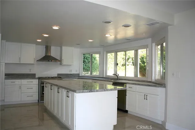a kitchen with white cabinets granite counter tops and a stove