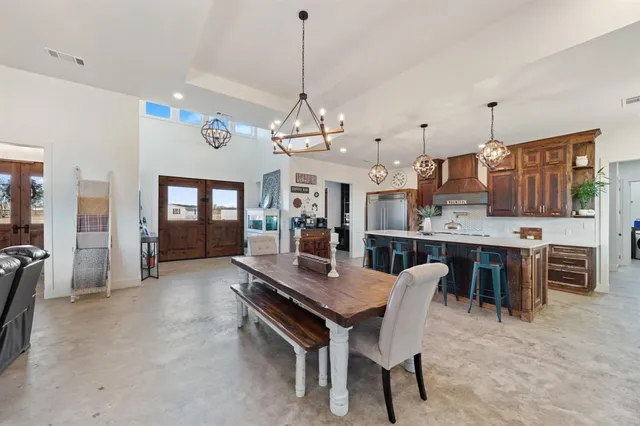 a dining room with wooden floor a chandelier a wooden table and chairs
