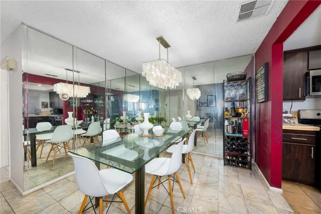 a view of a dining room with furniture a chandelier and kitchen view