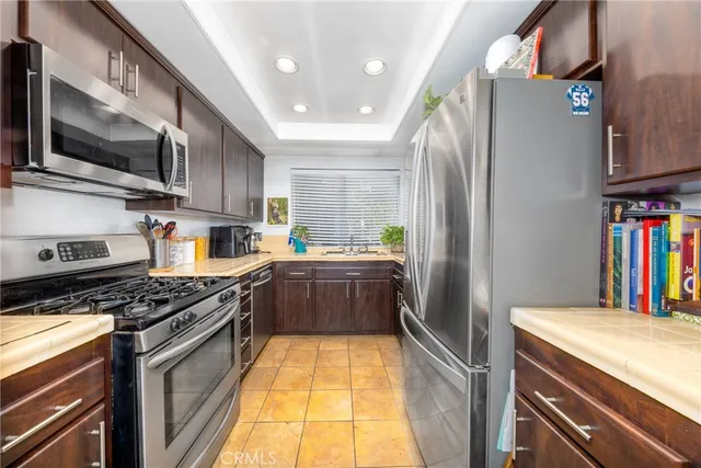 a kitchen with stainless steel appliances granite countertop a refrigerator a stove and a sink