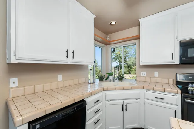 a kitchen with stainless steel appliances white cabinets a sink a stove a refrigerator and white cabinets