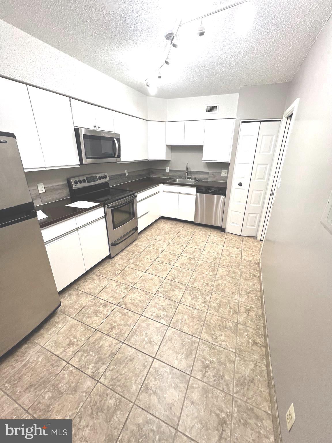 a large white kitchen with a stove a sink and a refrigerator