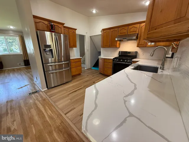 a kitchen with stainless steel appliances wooden floor and a refrigerator