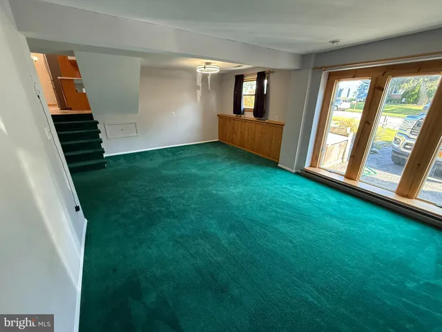 a view of an empty room with window and stairs