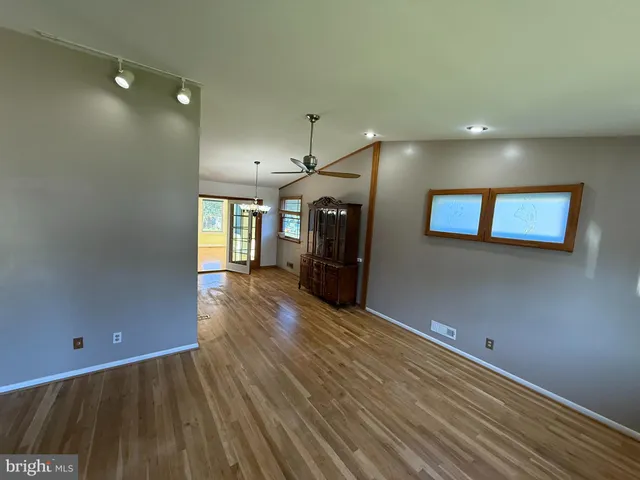 a view of a hallway with wooden floor and a living room