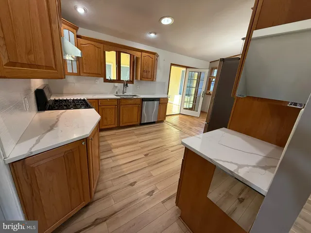 a large kitchen with kitchen island granite countertop wooden cabinets a sink and dishwasher