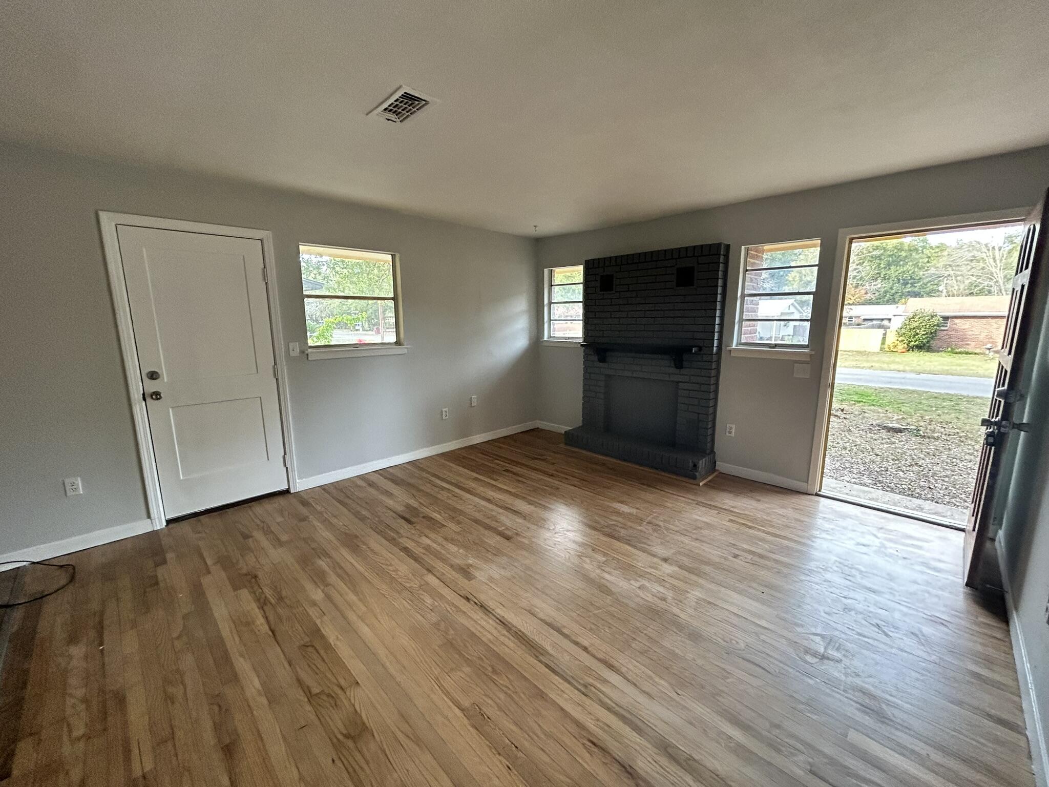 553 Purl Adams Avenue Crestview, FL 32539 - Photo 3 of 13 an empty room with wooden floor and windows