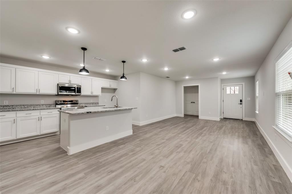 420 East 5th Street Bonham, TX 75418 - Photo 12 of 16 a large kitchen with stainless steel appliances granite countertop a large center island a stove a refrigerator white cabinets and wooden floor