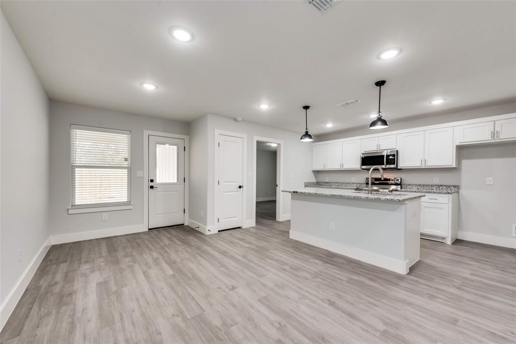 420 East 5th Street Bonham, TX 75418 - Photo 3 of 16 a kitchen with stainless steel appliances granite countertop a stove top oven a sink dishwasher and a refrigerator with wooden floor