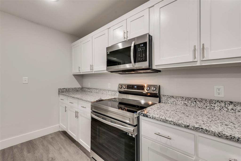 420 East 5th Street Bonham, TX 75418 - Photo 5 of 16 a kitchen with granite countertop white cabinets and a stove a oven with wooden floor