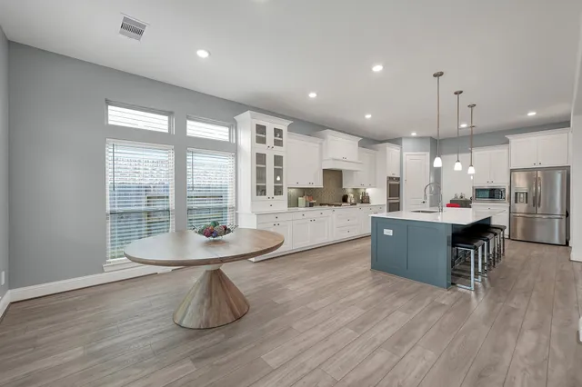 a large kitchen with kitchen island a island a sink a counter top space and stainless steel appliances