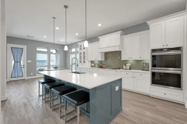 a large white kitchen with a large window appliances and cabinets