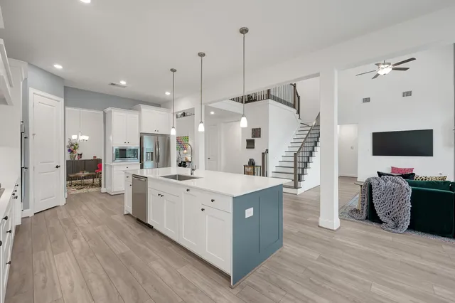 a large kitchen with stainless steel appliances kitchen island granite countertop a stove a sink and a wooden floors