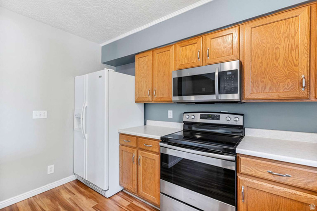 415 East 1150th Street North Logan, UT 84341 - Photo 11 of 38 Kitchen featuring wood-finish flooring, natural wood cabinetry, light-toned countertops, and stainless steel appliances including a range and microwave