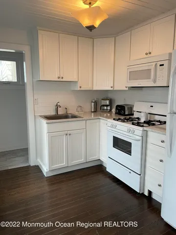 a white kitchen with granite top and stainless steel appliances