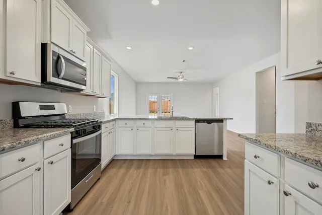 a kitchen with granite countertop white cabinets and white appliances