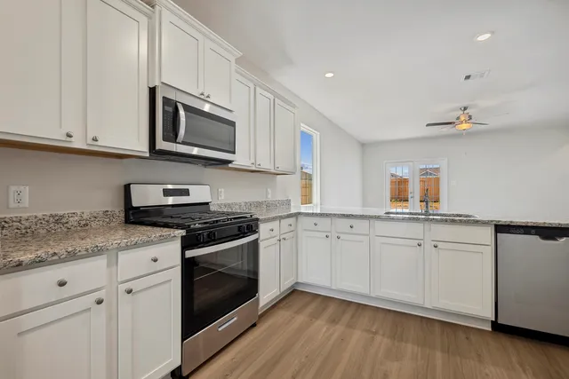 a kitchen with stainless steel appliances granite countertop white cabinets a sink and dishwasher