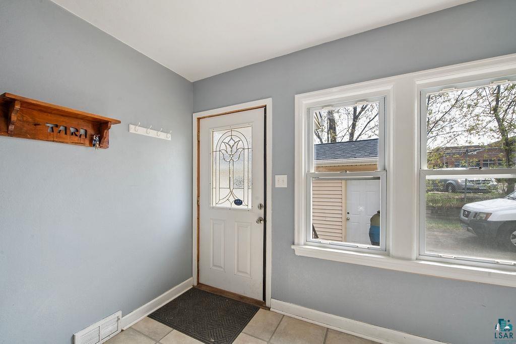122 3rd Street Cloquet, MN 55720 - Photo 7 of 42 Entryway featuring a white door with decorative glass inserts, two single-hung windows, light blue walls, and tiled flooring
