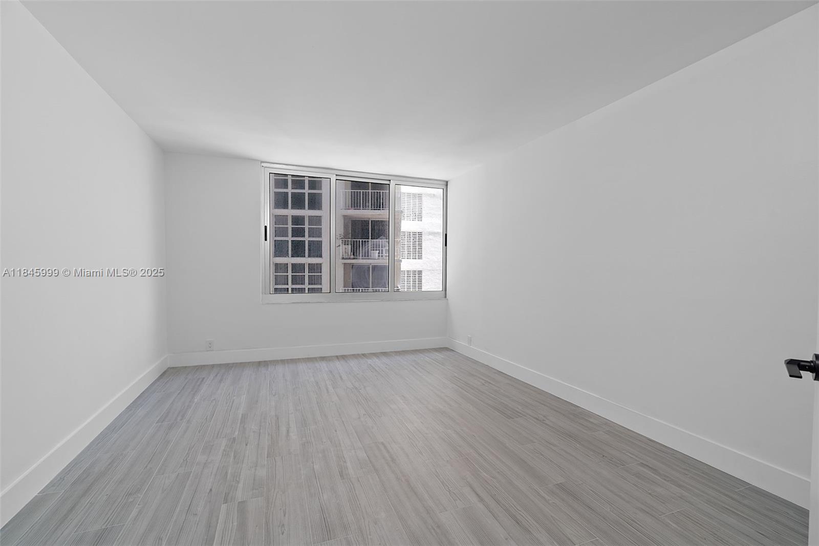 1200 West Avenue, Unit 521 Miami Beach, FL 33139 - Photo 5 of 51 an empty room with wooden floor and windows